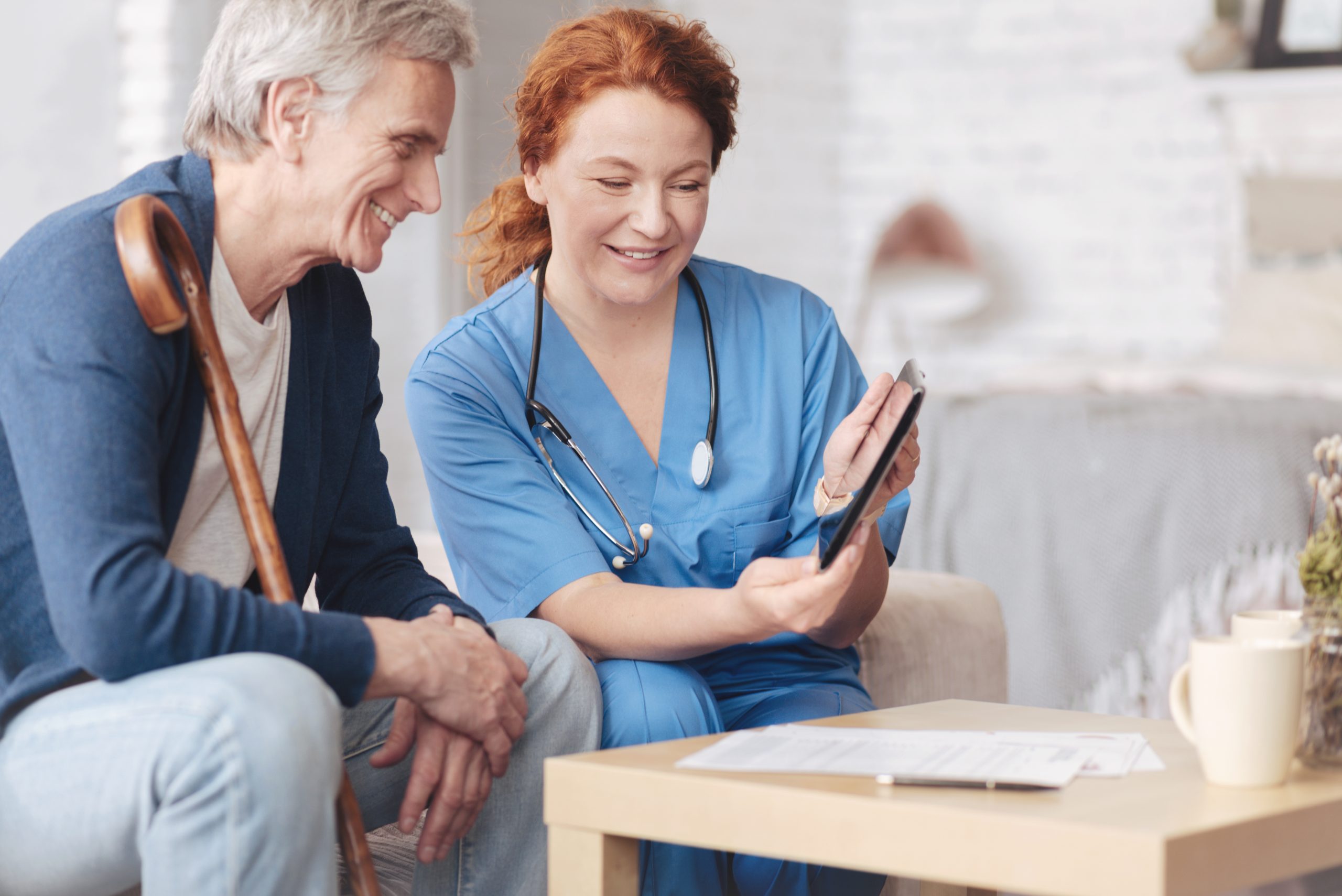 Friendly senior patient and nurse looking tablet computer